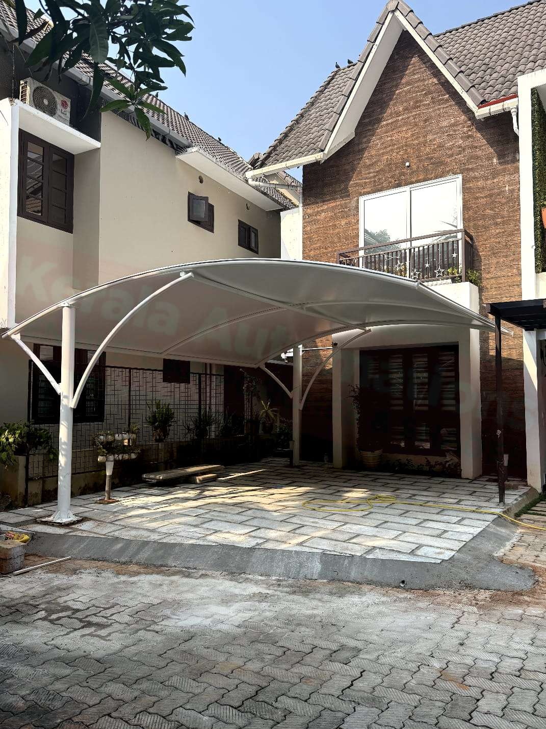 Modern tensile car porch design built in Mallappally, Kerala using latest cantilever and roofing styles