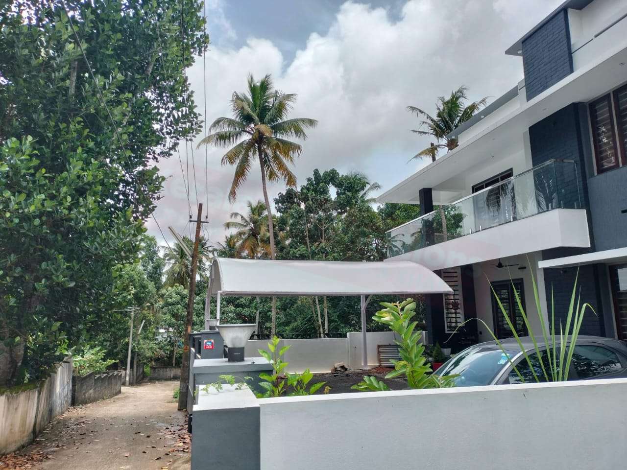 Modern tensile car porch design built in Oachira, Kerala using latest cantilever and roofing styles